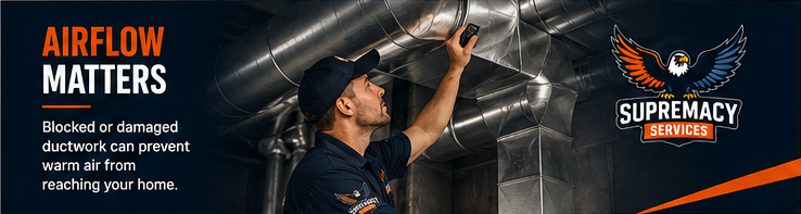 A professional HVAC technician in a Supremacy Service uniform carefully inspecting the internal components of a residential furnace.